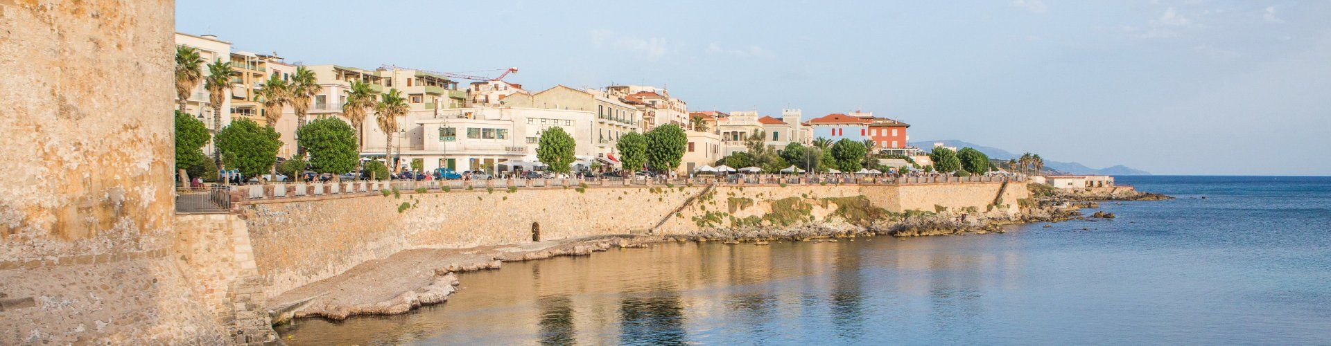 The silhouette of Alghero behind the city wall refelected in the calm sea