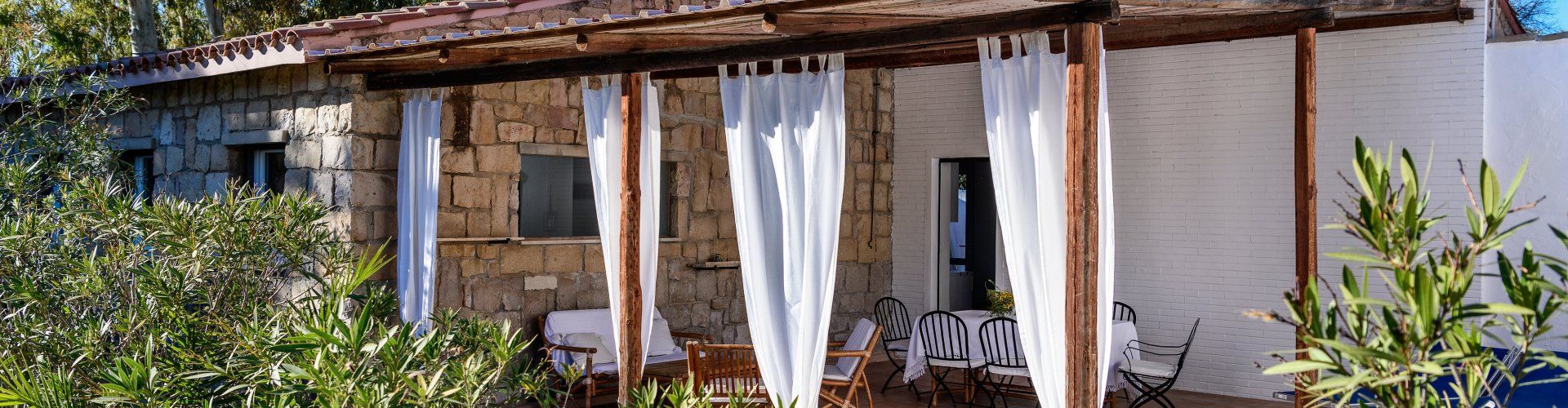 Casa Su Faru 3 | Roofed terrace with comfortable sofacorner, table and sunbeds Roofed terrace of Su Faru 3 Pula with sofacorner, table and sunbeds