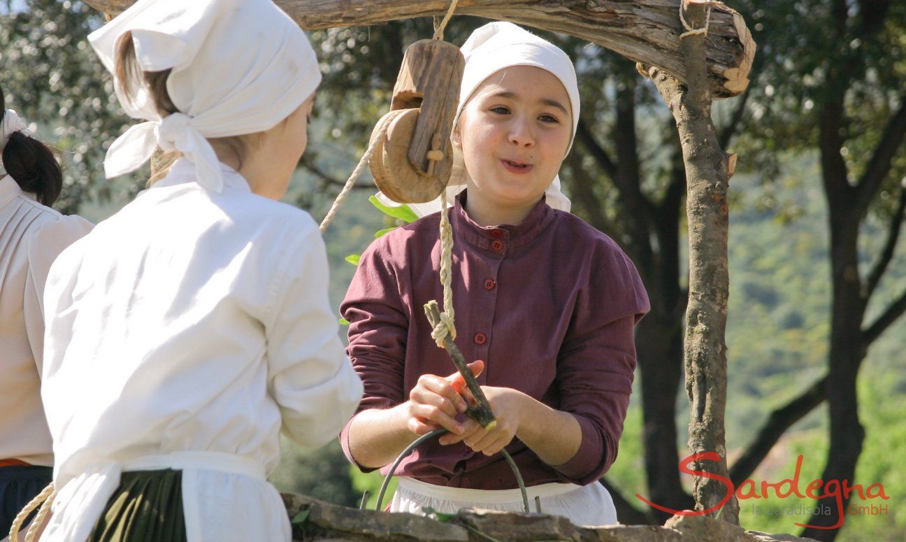 Two young girls taking water from an old water well