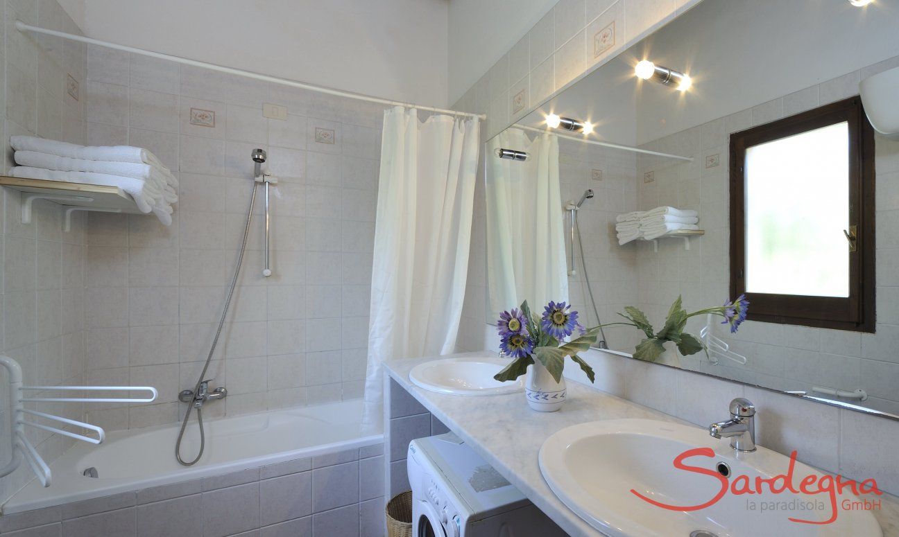 Bathroom with bathtub, two sinks and washing machine