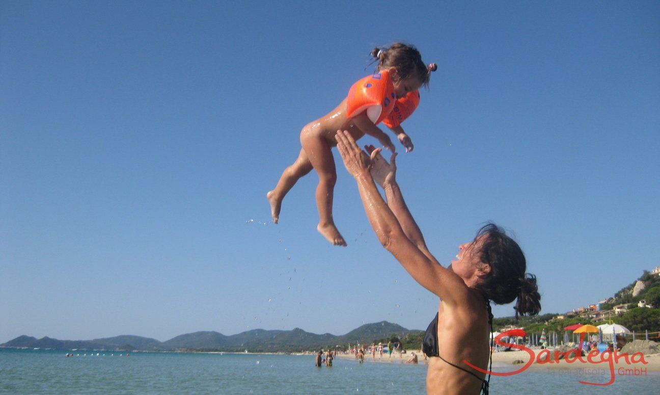 Mother throwing her baby in the air at the beach of Monte Nai