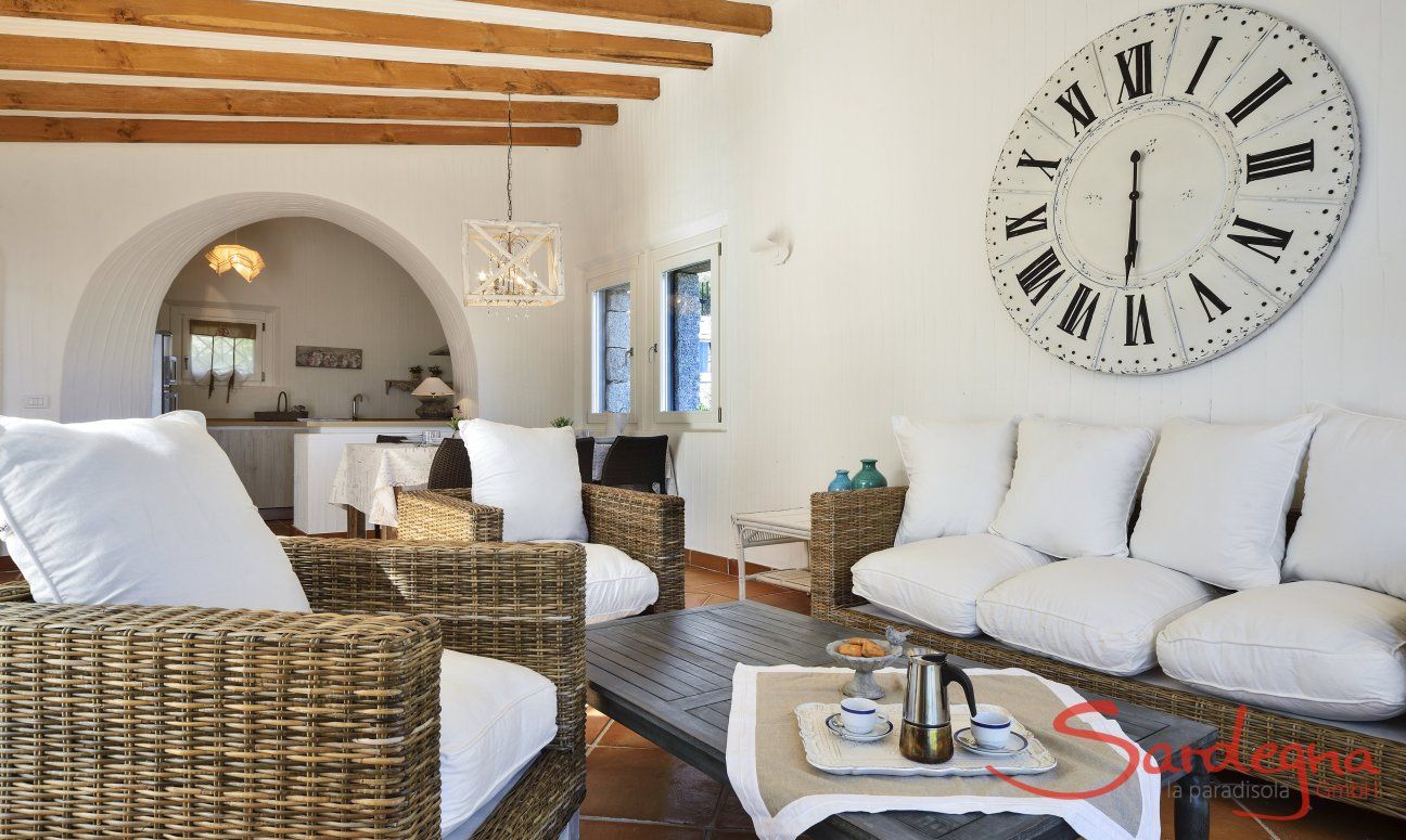 Li Conchi 10 | Sofa corner with large wall clock and dining area in the background Sofa Corner and a big watch on the wall Li Conchi 10, Cala Sinzias