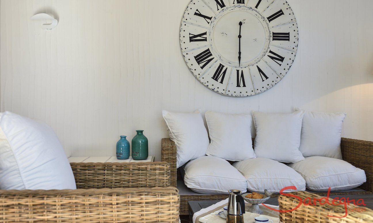 Li Conchi 10 | Cozy wicker sofa and large wall clock Sofa Li Conchi 10, Cala Sinzias