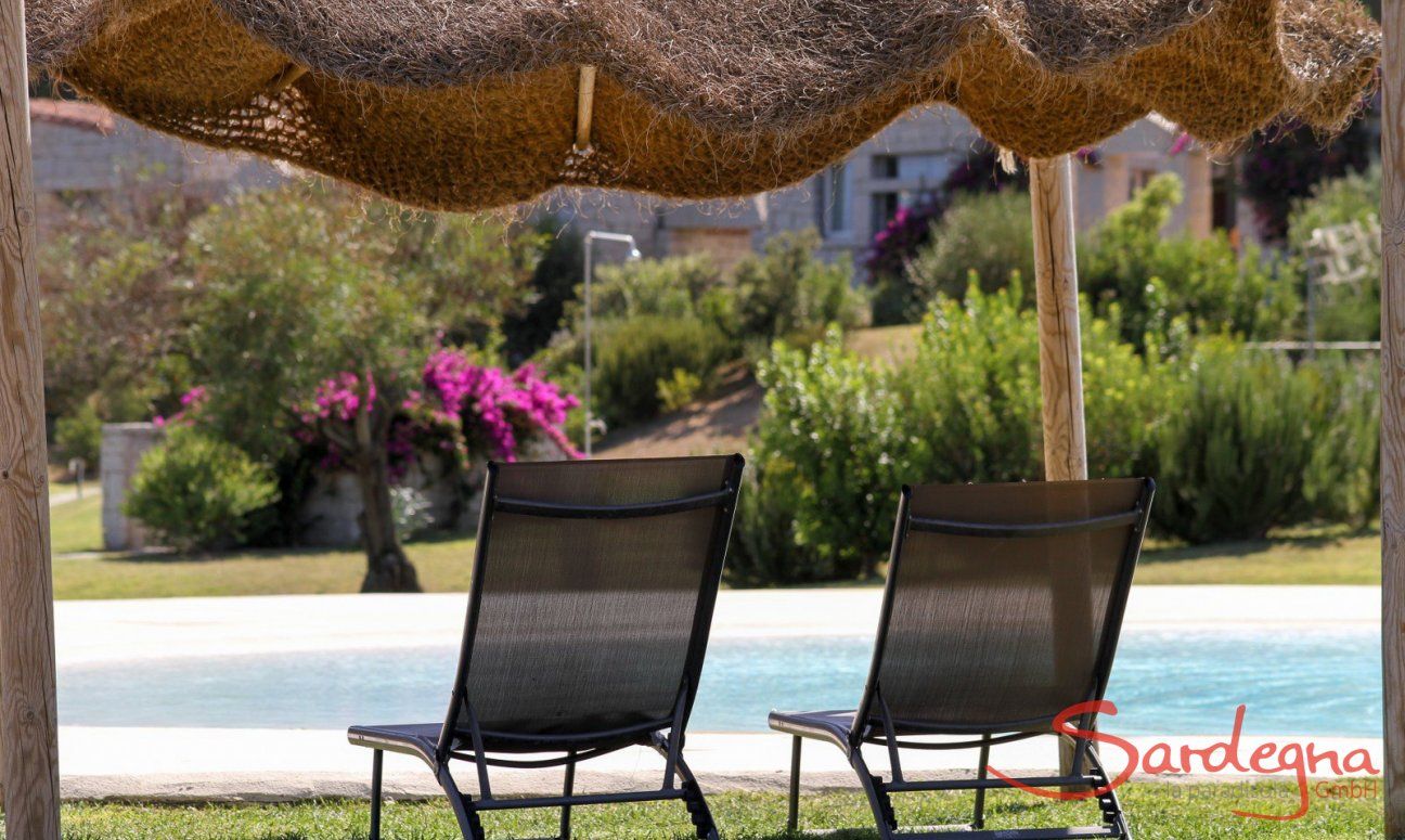 Sunbeds underneath an ombrella by the pool of Li Conchi