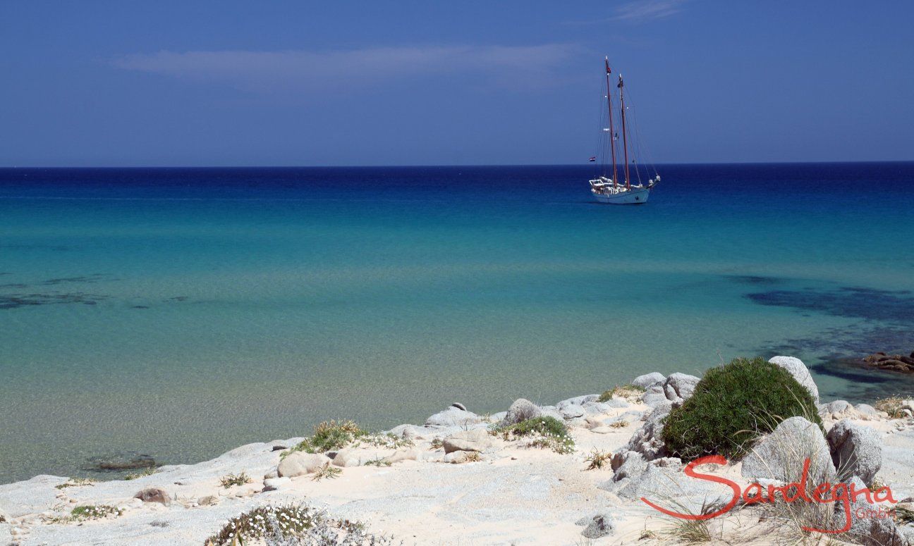 Beach in the south of Sardinia with turquoise water and sailing ship