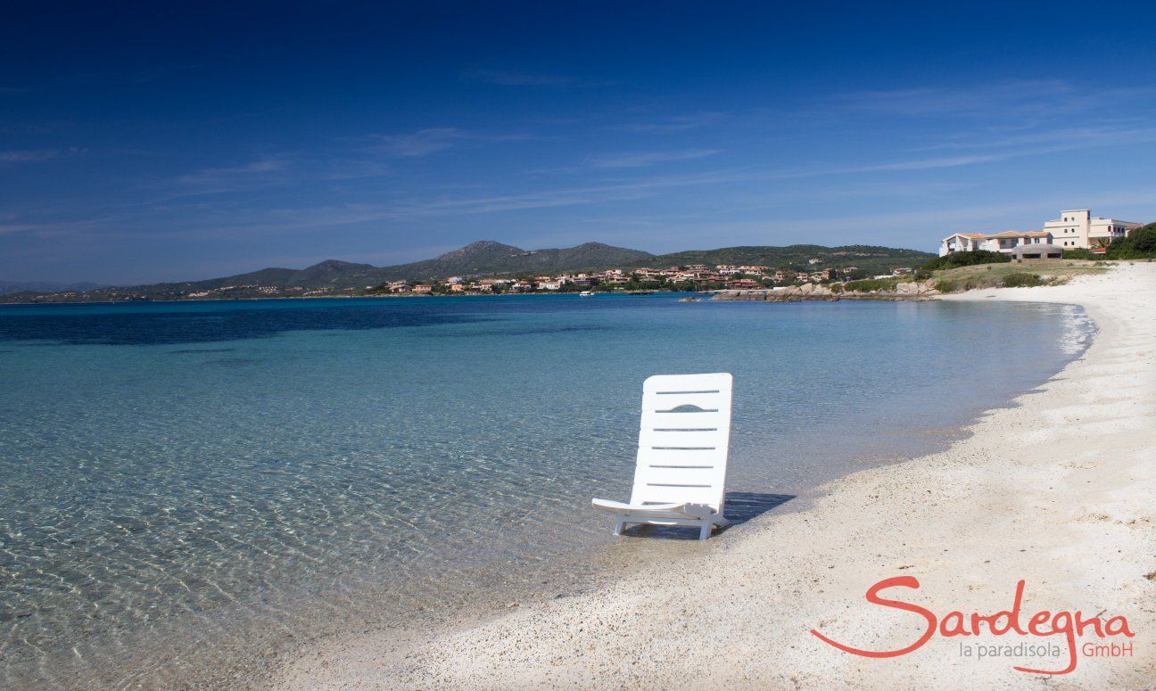 White sun lounger in the crystal clear water on the beach of Golfo Aranci