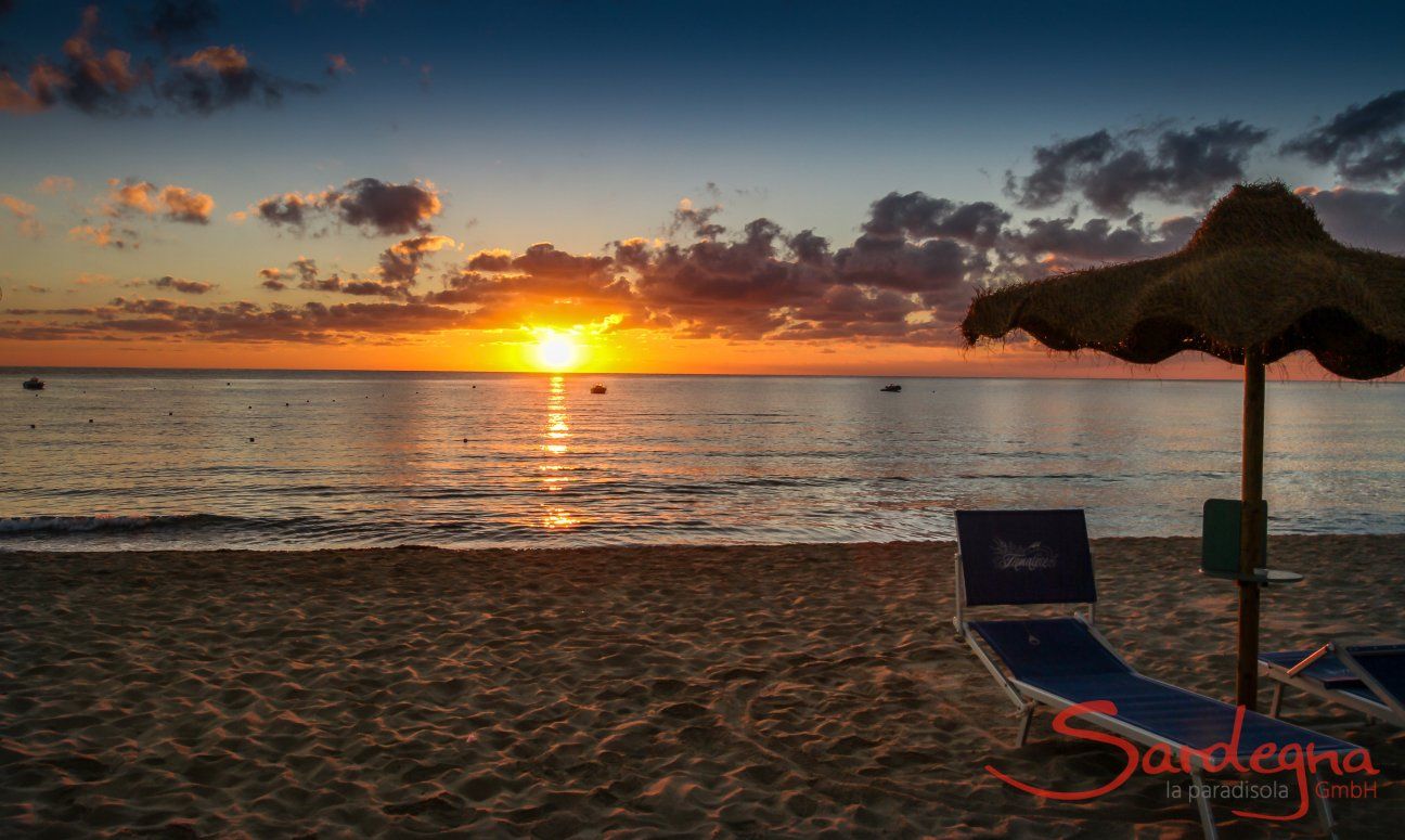 The sunrise over the sea of Cala Sinzias stings the horizon in bright orange