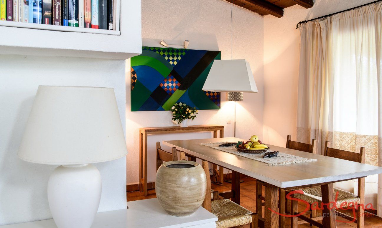 Villa Kika | Dining table with fine artwork on the wall behind it Dining table with fine artwork on the wall behind it