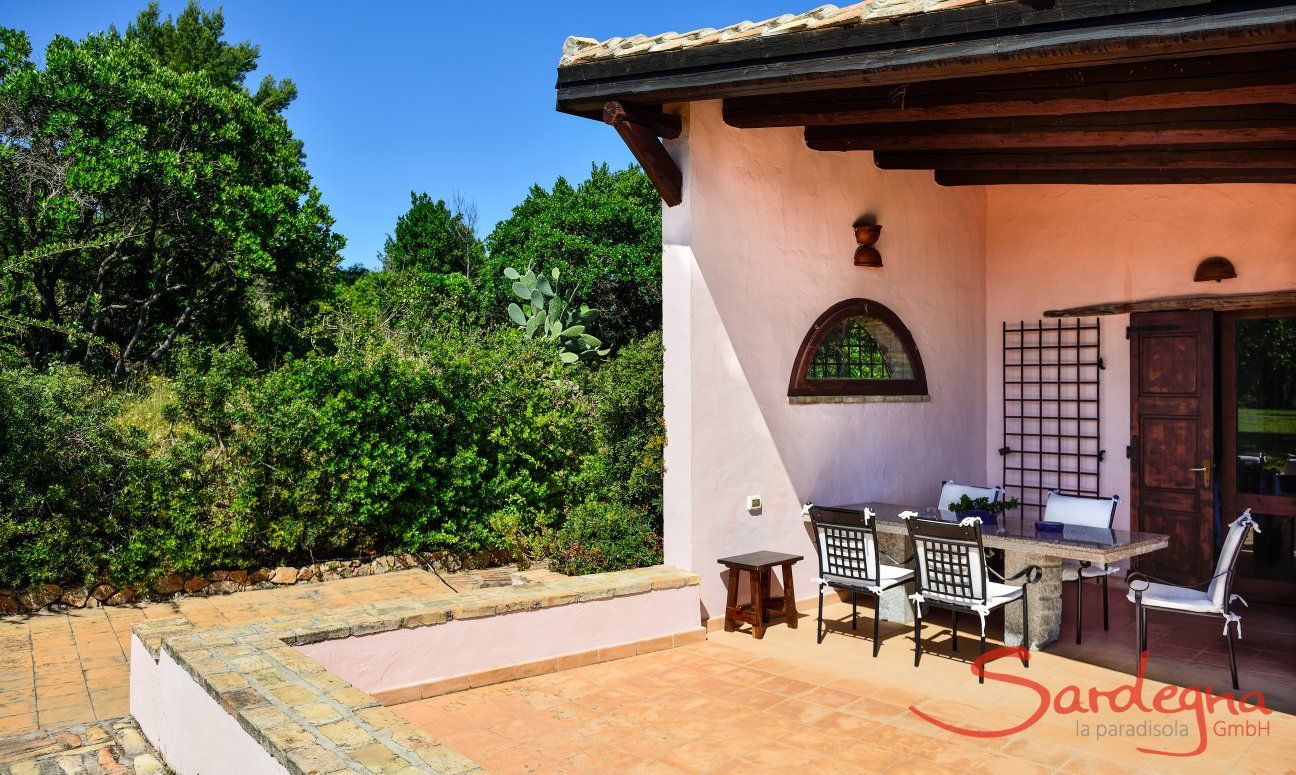 Roofed terrace with dining table and view towards the green surroundings