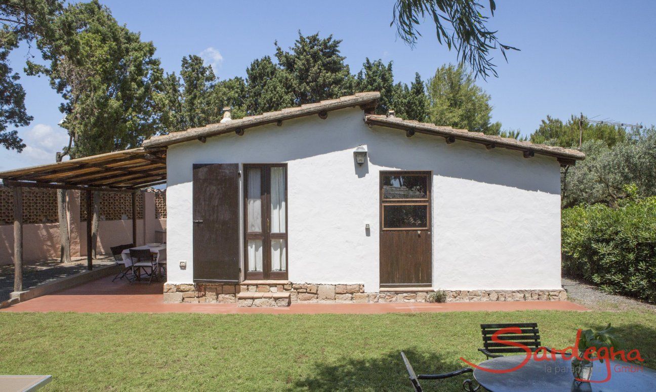 Casa Su Faru 5 | View of the garden, the house with roofed terraca and entrance doors to bedroom and livingroom View of the garden and house