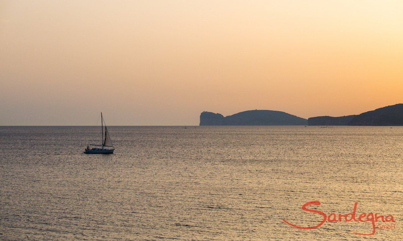 The sea seen from Alghero at sunset with a sailing boat and Capo Caccia on the horizon