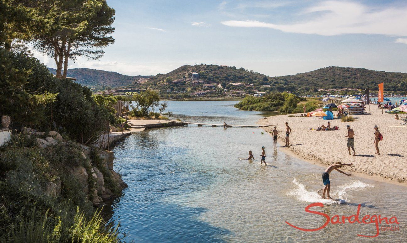 Kids play in the shallow water of the lagoon of Porto Taverna