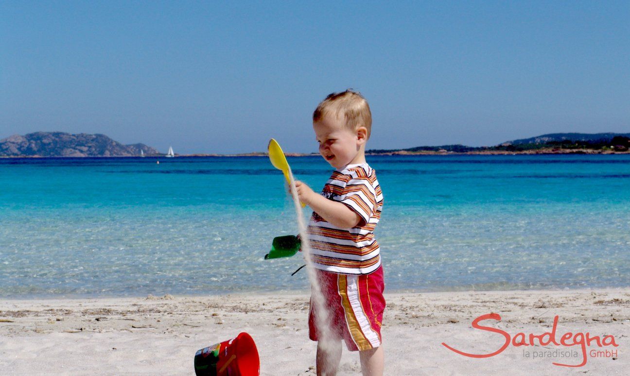 Child playing with the white sand of Porto Istana, 7 miles south of Olbia