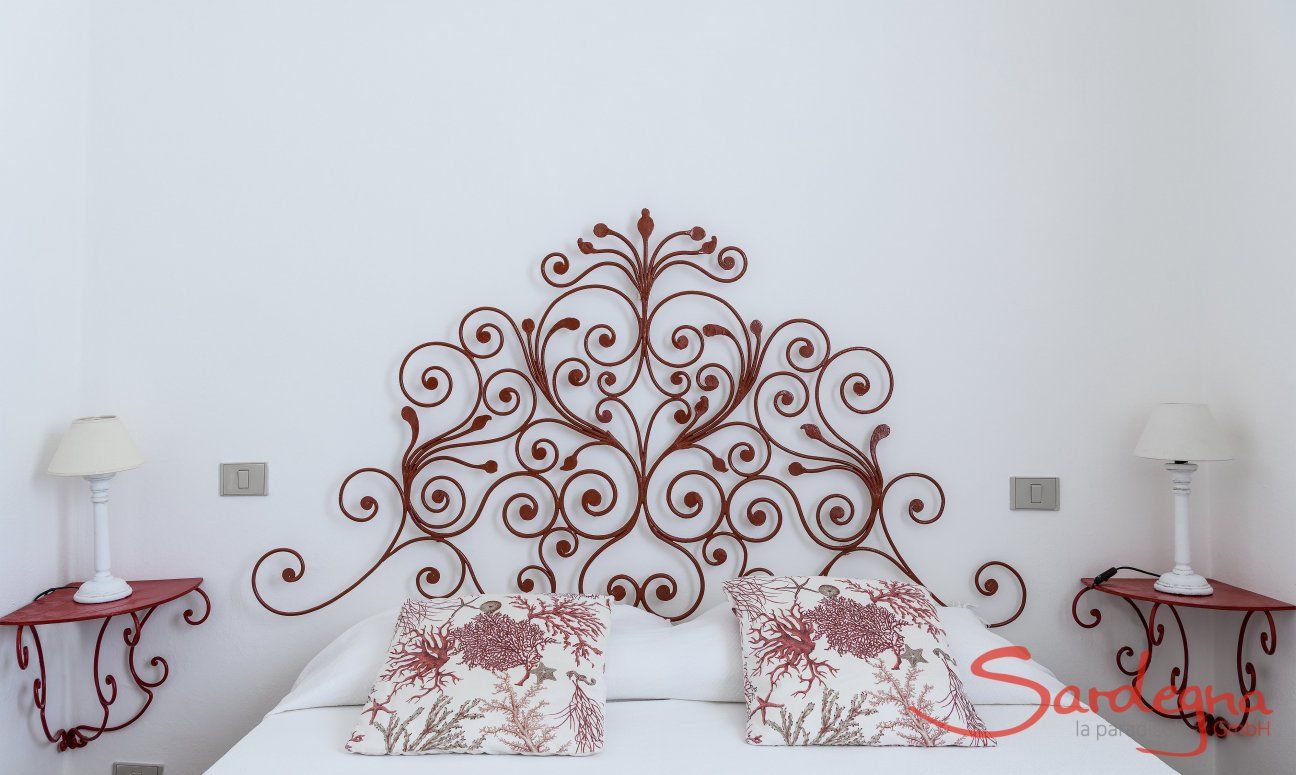 Casa Su Faru 2 | Bedroom 1 with red, wrought iron bed-head and night tables Bed with red, wrought iron bed-headand night tables in Su Faru 2 Pula
