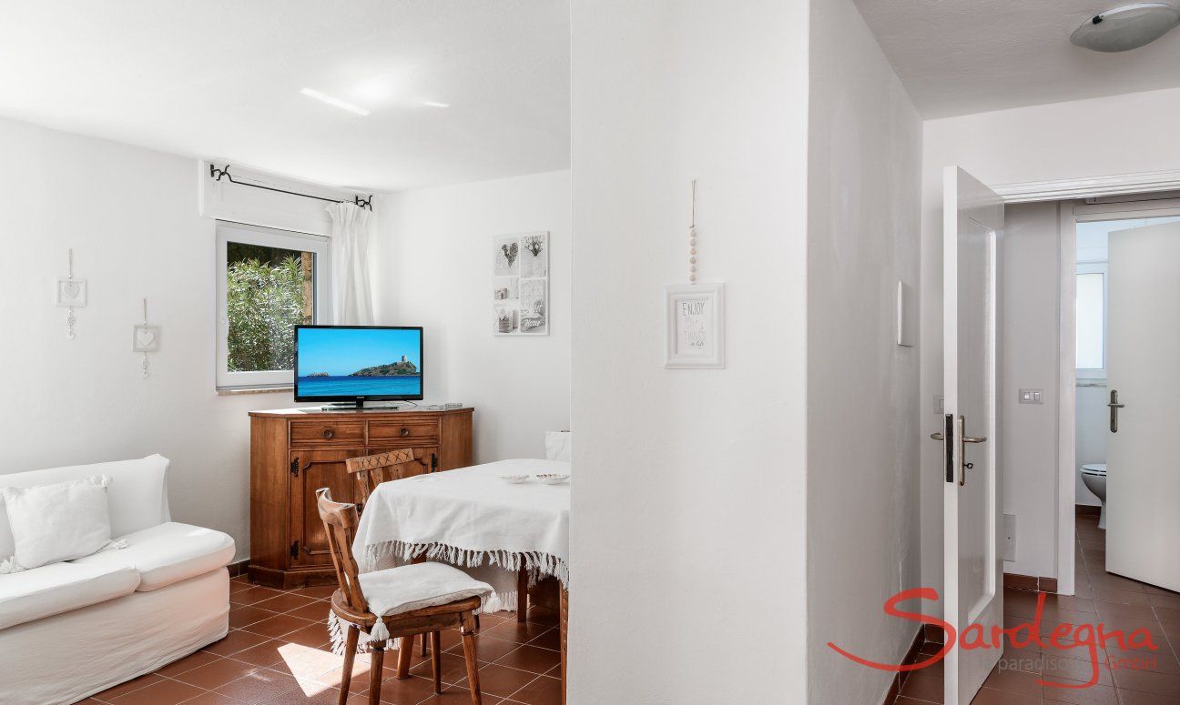 Casa Su Faru 3 | Living room with table, couch, TV and access to two of the bedrooms Living room with table, couch, TV and access to the bedrooms of Su Faru 3 Pula