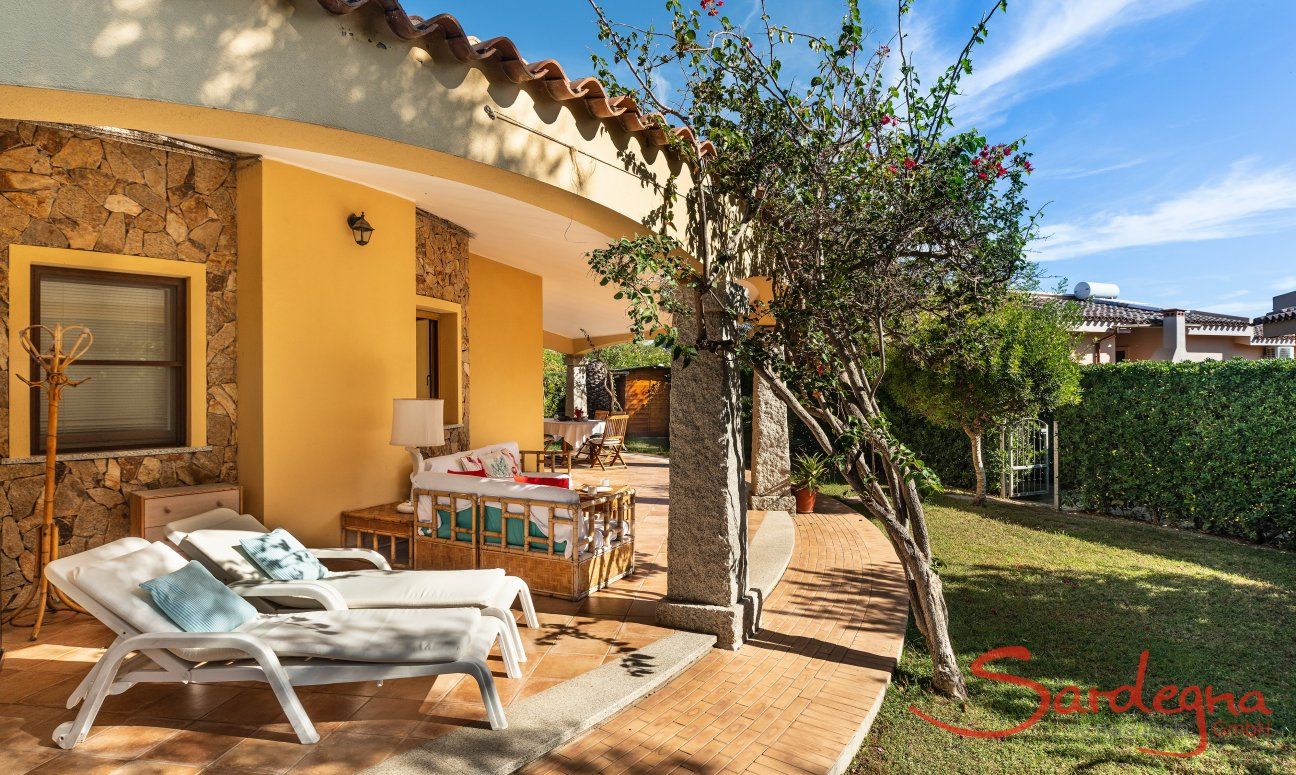 Villa Tiziana 11 | A terrace lines part of the house and boosts comfortable sun loungers, an outside sofa corner and a dining table Portrait of the house