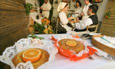 Presentation of orange cakes with the people preparing them in the background, all of them dressed in typical sardinian costumes