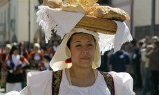 Woman in sardinian costume who is carrying a basket full of bread on her head