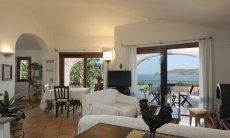 Villa Cala Ginepro | Bright living room with terrace access and sea view Bright living room with terrace access and sea view