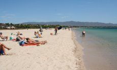 Taking a sunbath on the white sand of the beach Poetto close to Cagliari