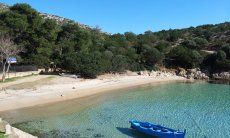 Traditional, blu fisherboat floats on the crystal clear water of the bay of Cala Moresca, Golfo Aranci