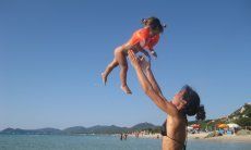Mother throwing her baby in the air at the beach of Monte Nai