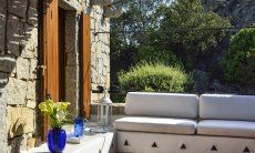 Brick-built outsite lounge in front of green shrubs and ganite rocks, typical for the Costa Smeralda