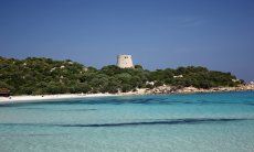 Crystal clear water, white sand and the old spanish tower in the bay of Cala Pira