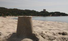 Close up of the sandmodel of the spanish tower of Cala Pira, in the background the real tower