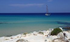 Beach in the south of Sardinia with turquoise water and sailing ship