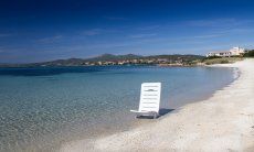 White sun lounger in the crystal clear water on the beach of Golfo Aranci