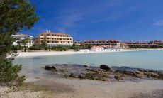 White beach and transparent sea just in front of the skyline of Golfo Aranci