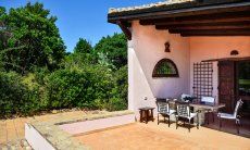 Roofed terrace with dining table and view towards the green surroundings