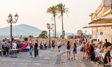 Boardwalk of Alghero with old cannons, high palm trees and view along the coastline