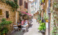 Narrow pedestrian alley of the old town of Alghero with tables of a restaurant to eat outside