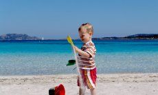 Child playing with the white sand of Porto Istana, 7 miles south of Olbia