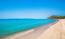 Turqoise water and white sand of Geremeas, in the background the coastline of Cagliari