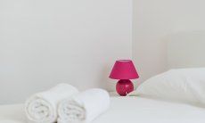 Villa Pola | White bed with towels and nightlamp in pink White bed with towels and nightlamp in pink