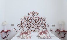 Casa Su Faru 2 | Bedroom 1 with red, wrought iron bed-head and night tables Bed with red, wrought iron bed-headand night tables in Su Faru 2 Pula