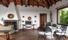 Villa Fiorita | Living room with fire place, TV, dining table and access to the kitchen Portrait of the villa