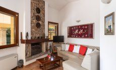 Villa Tiziana 11 | Comfortable sofa corner with TV and fireplace for the colder and air conditioning for the warm days Portrait of the house