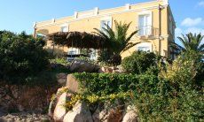 Villa Aquila Alta | Villa Aquila surrounded by rocks, palm trees and bushes Sardinia